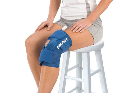Woman sitting on a white stool with the AIRCAST Knee Cryo/Cuff on her knee