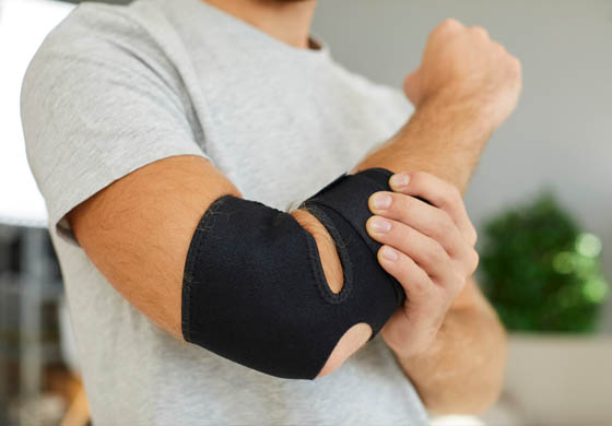 Close-up of young, fit man with his elbow in a brace