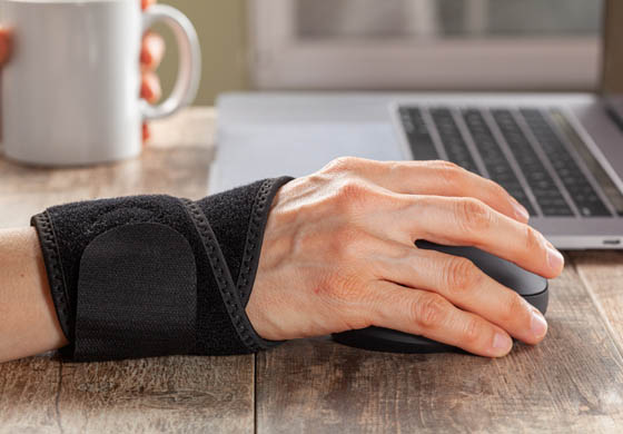 Close-up of man's hand in a wrist brace working at his compter