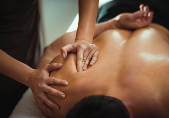 Massage therapist working on a male patient's shoulder