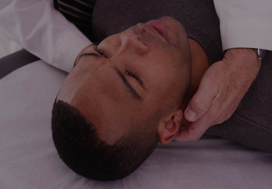 Young male laying on his back while a doctor's hands investigate his neck and head following a concussion