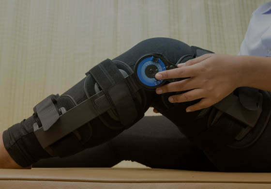Woman sitting sideways with her leg bent up and showing off her black and blue custom knee brace