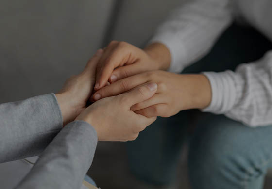Close-up of hands as a therapist holds the hands of her patient