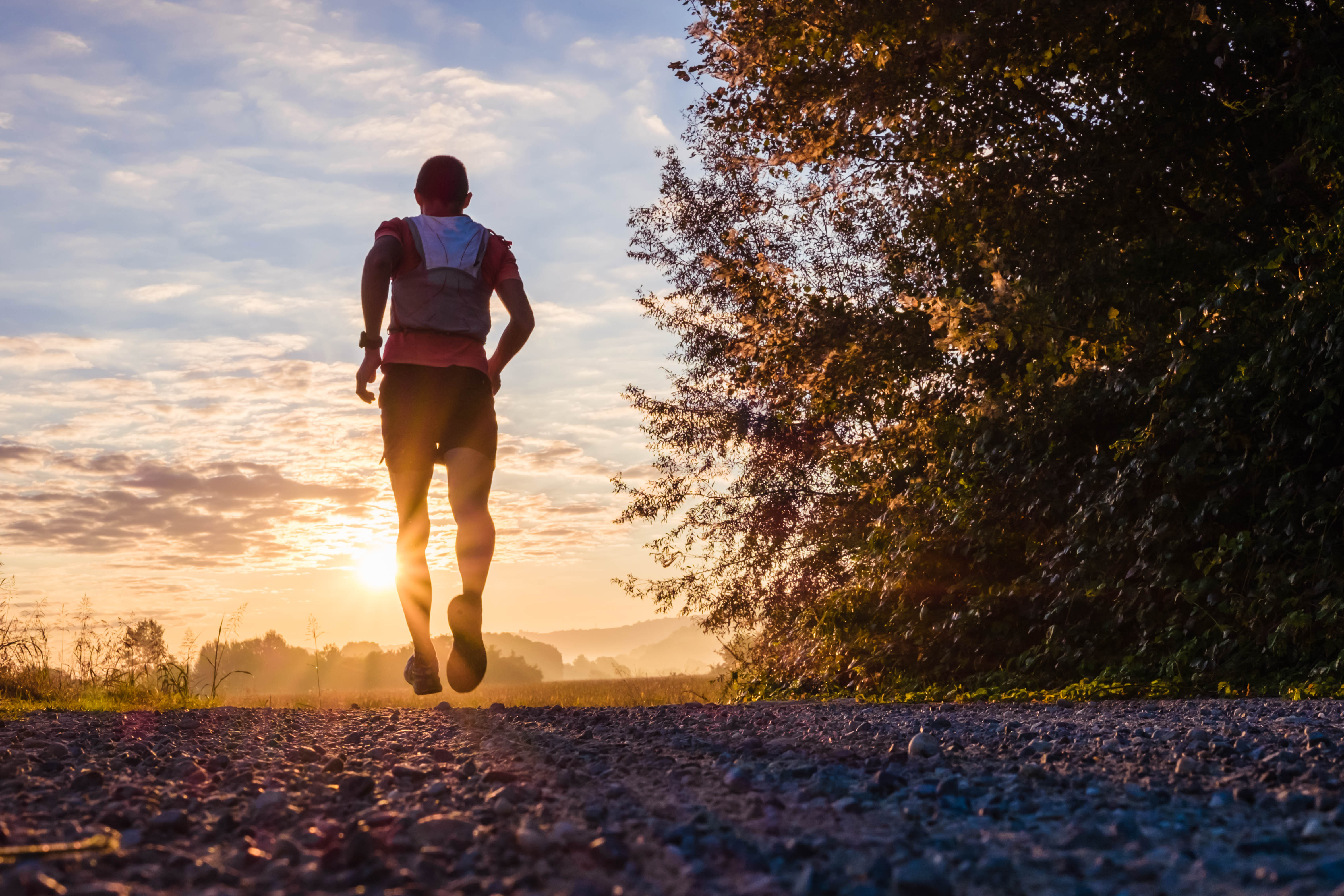 Man running on a dirt path in the evening, as the sun sets